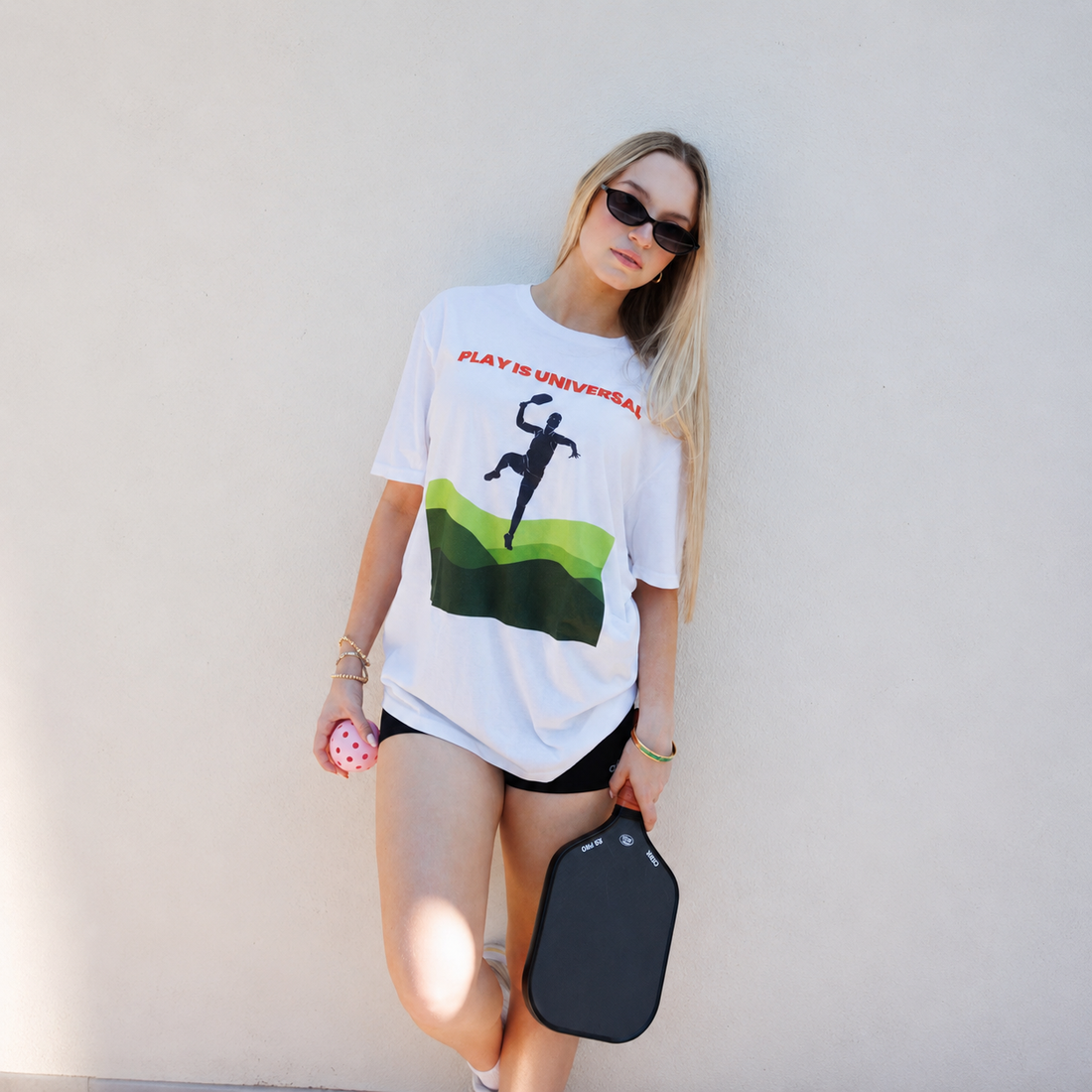 Player in the white Courtelane Play is Universal pickleball tee on a sunny day