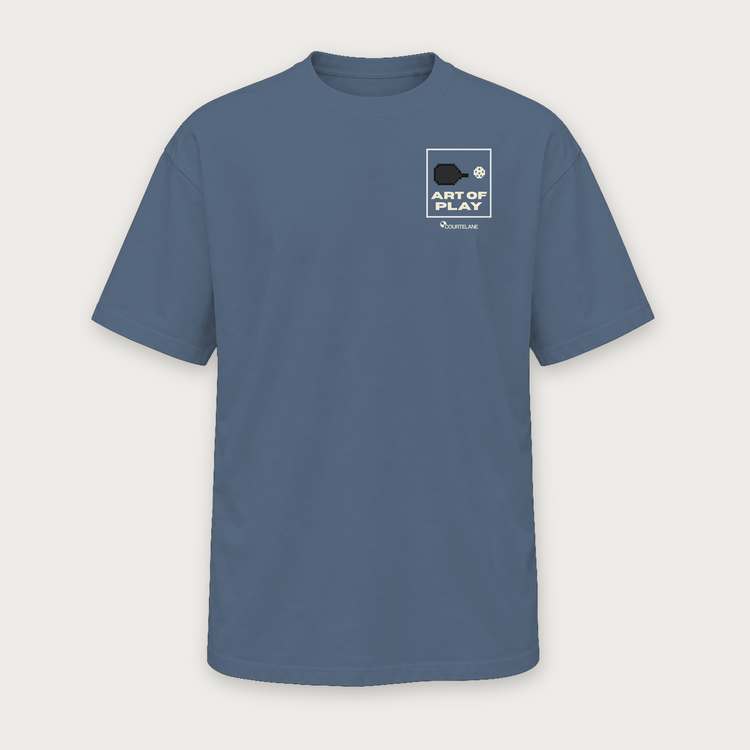 The Art of Play pickleball tee by Courtelane in slate blue, front with Art of Play box print